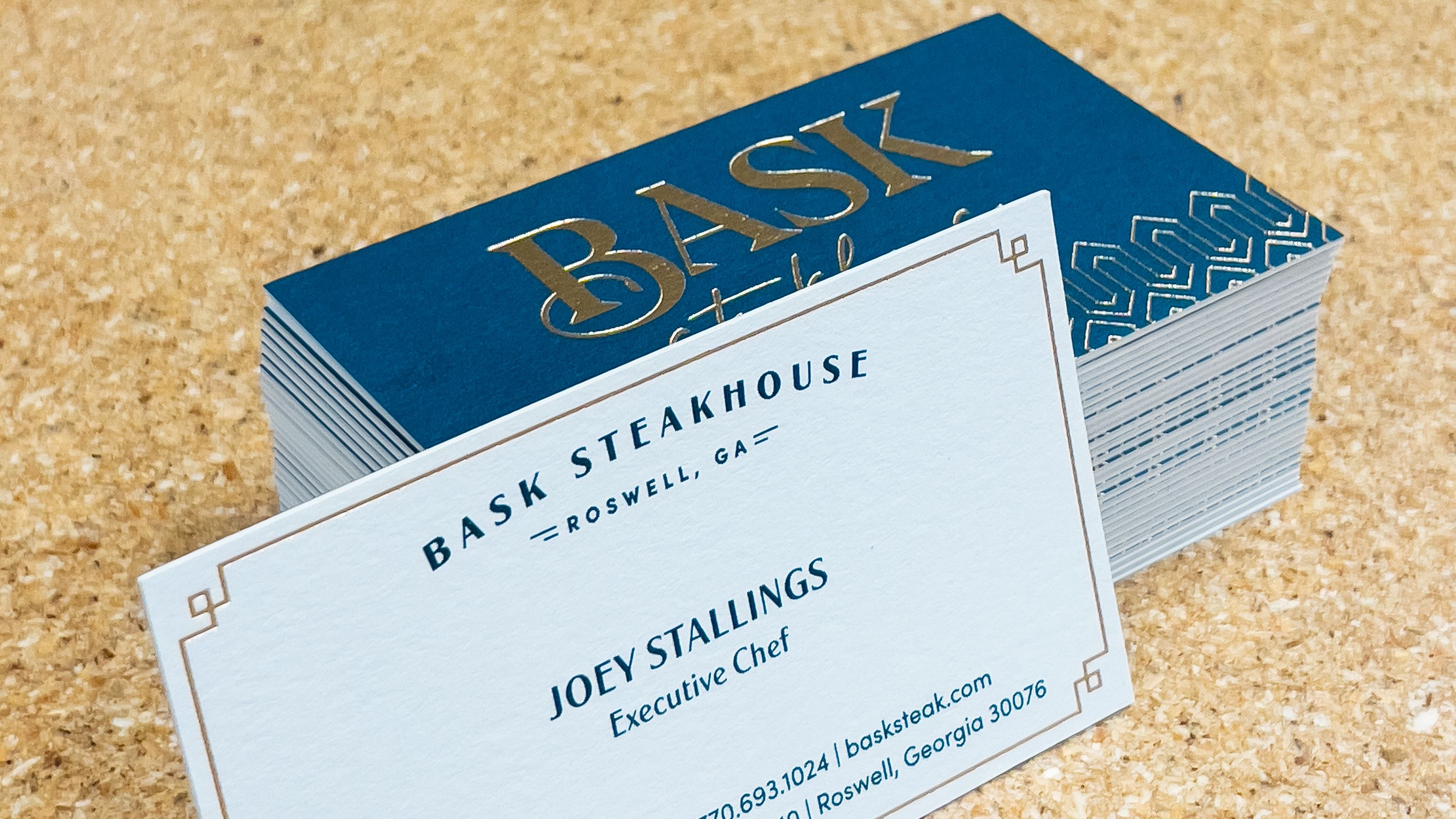 An image of a business card with gold foil stamping and a custom blue ink