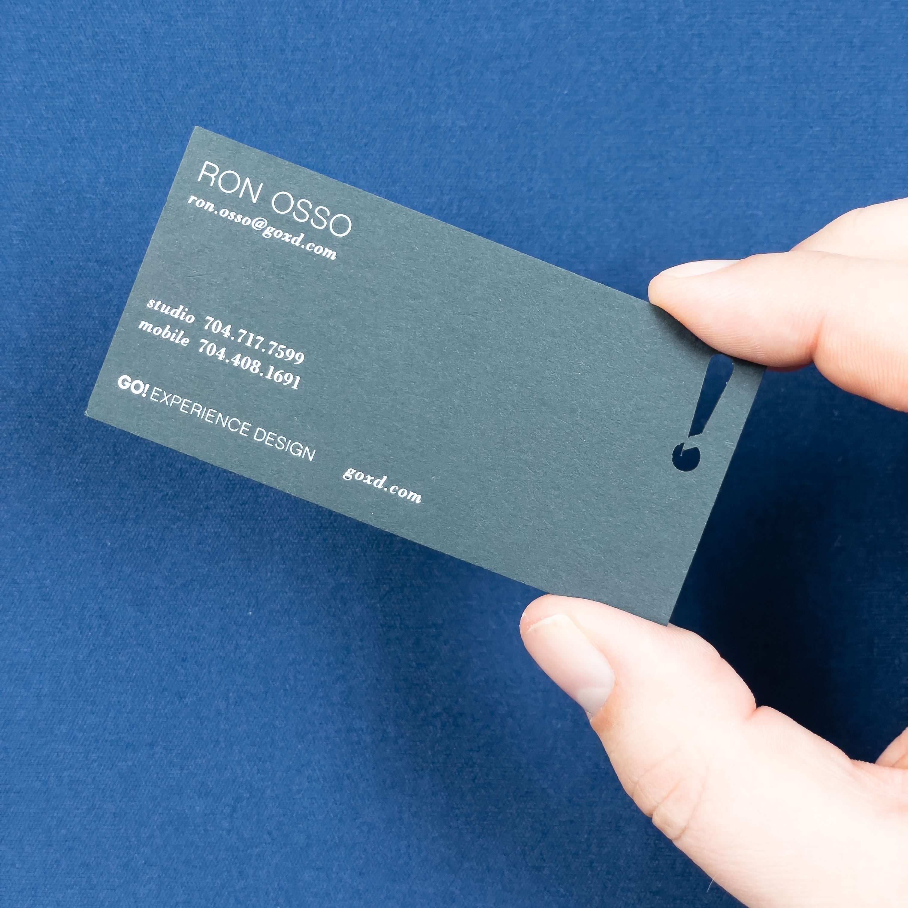 An image of a business card with an exclamation point die cut out of the card.