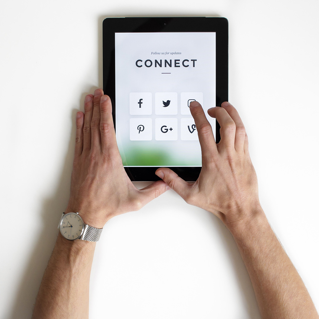 A person's hands on a tablet selecting a social media icon