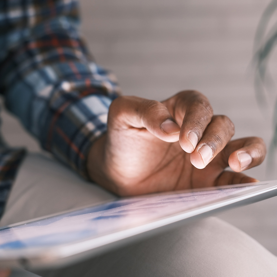 A person's hand lit by their tablet's screen