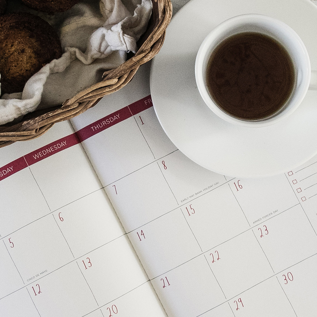 A calendar under a cup of coffee and saucer