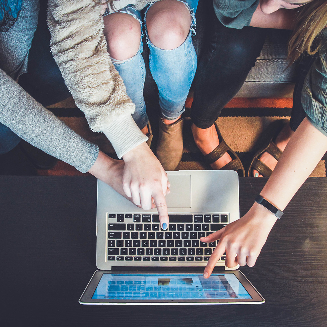 Three woman looking at a laptop and pointing