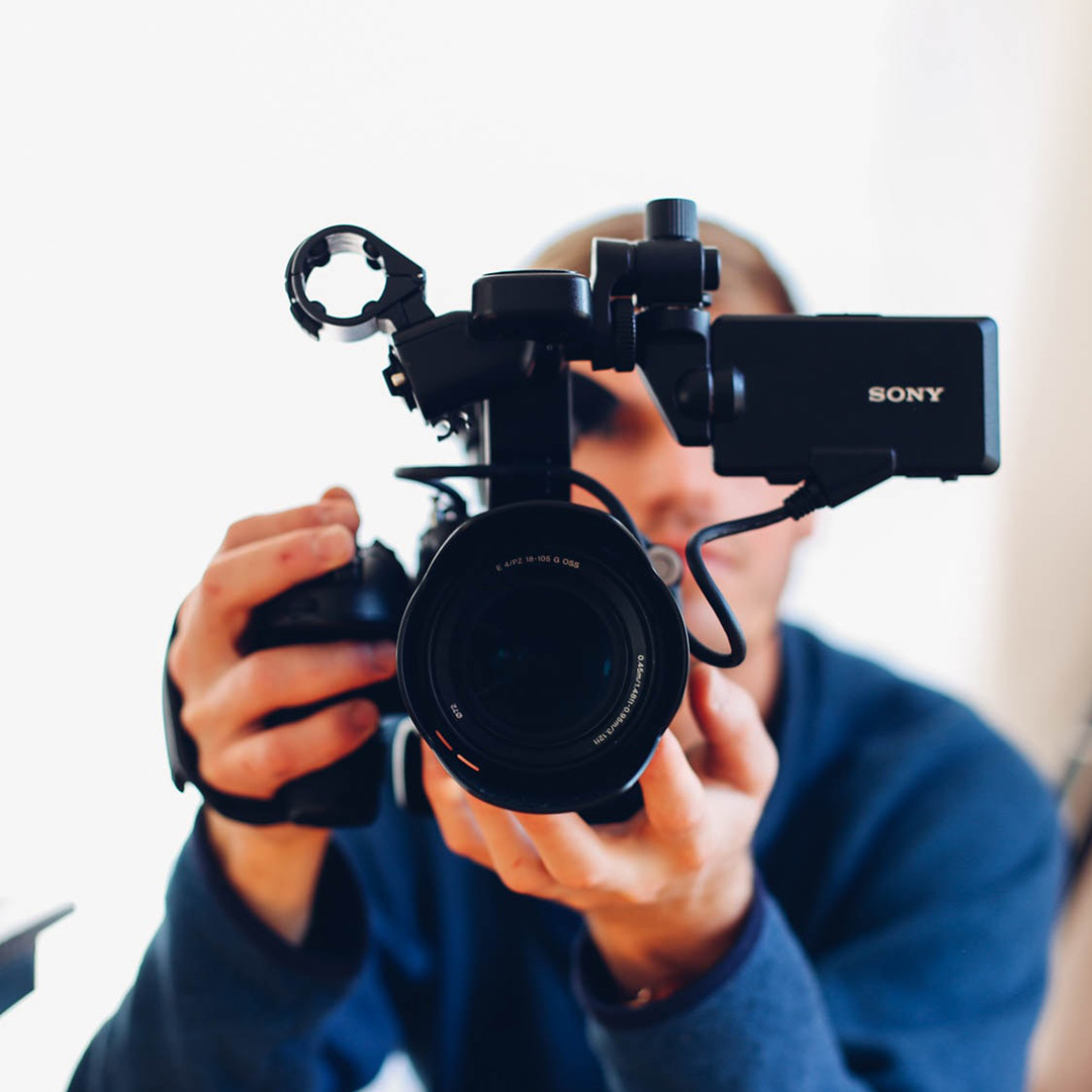 A man pointing a digital video camera at you