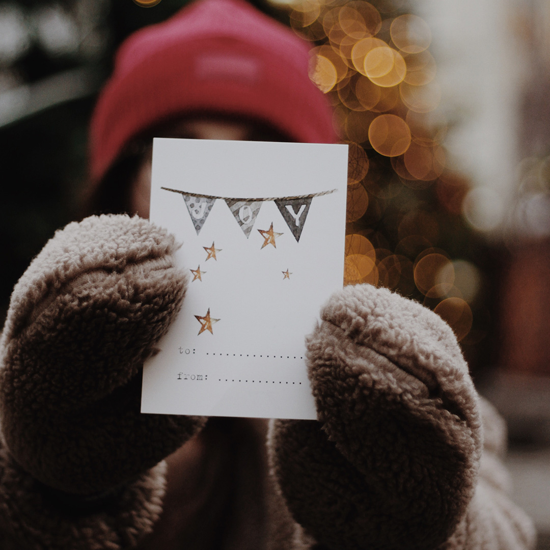 A woman holding up a seasonal greeting card