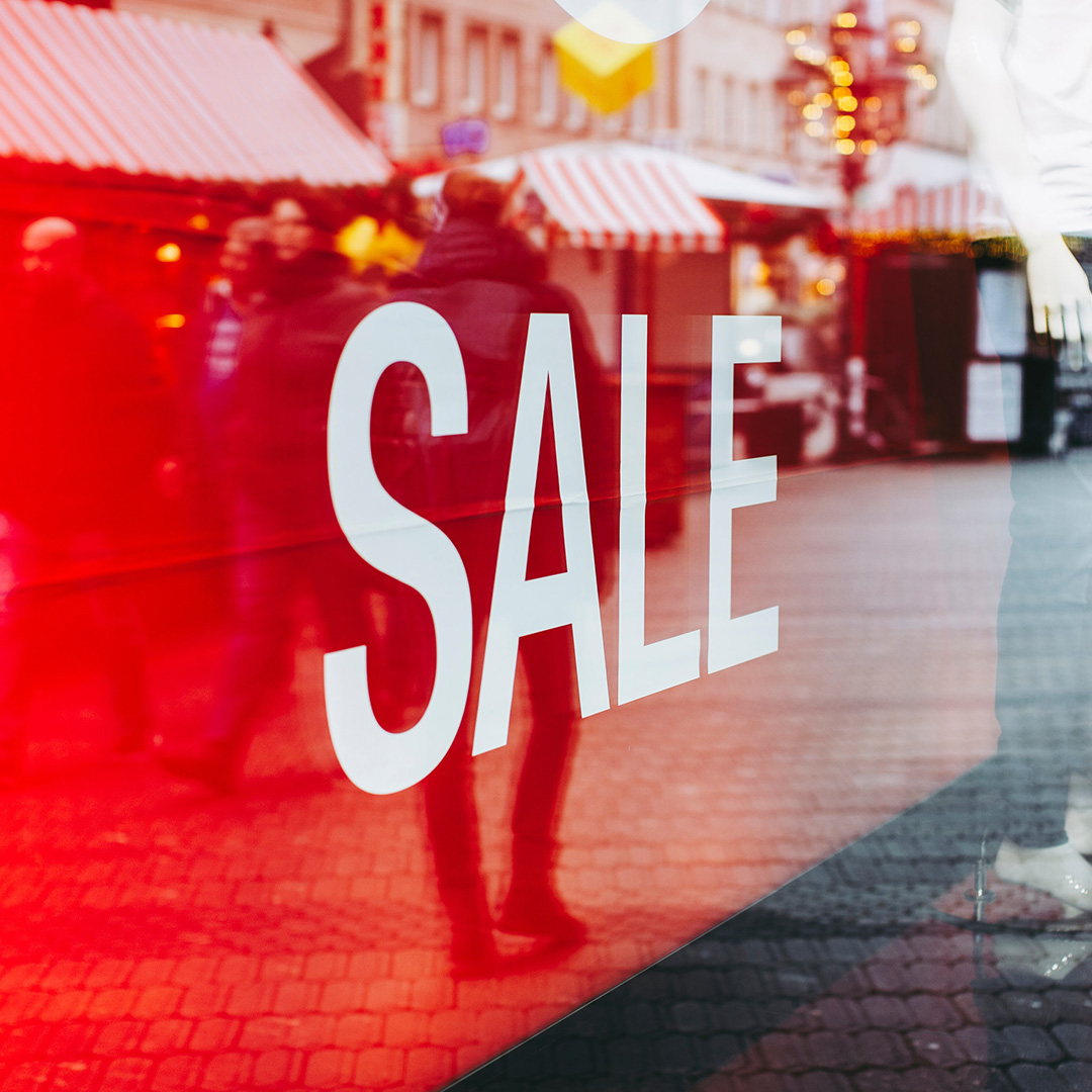 A sale sign on a business window facing the sidewalk