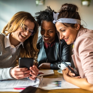 Three women looking at social media on a phone