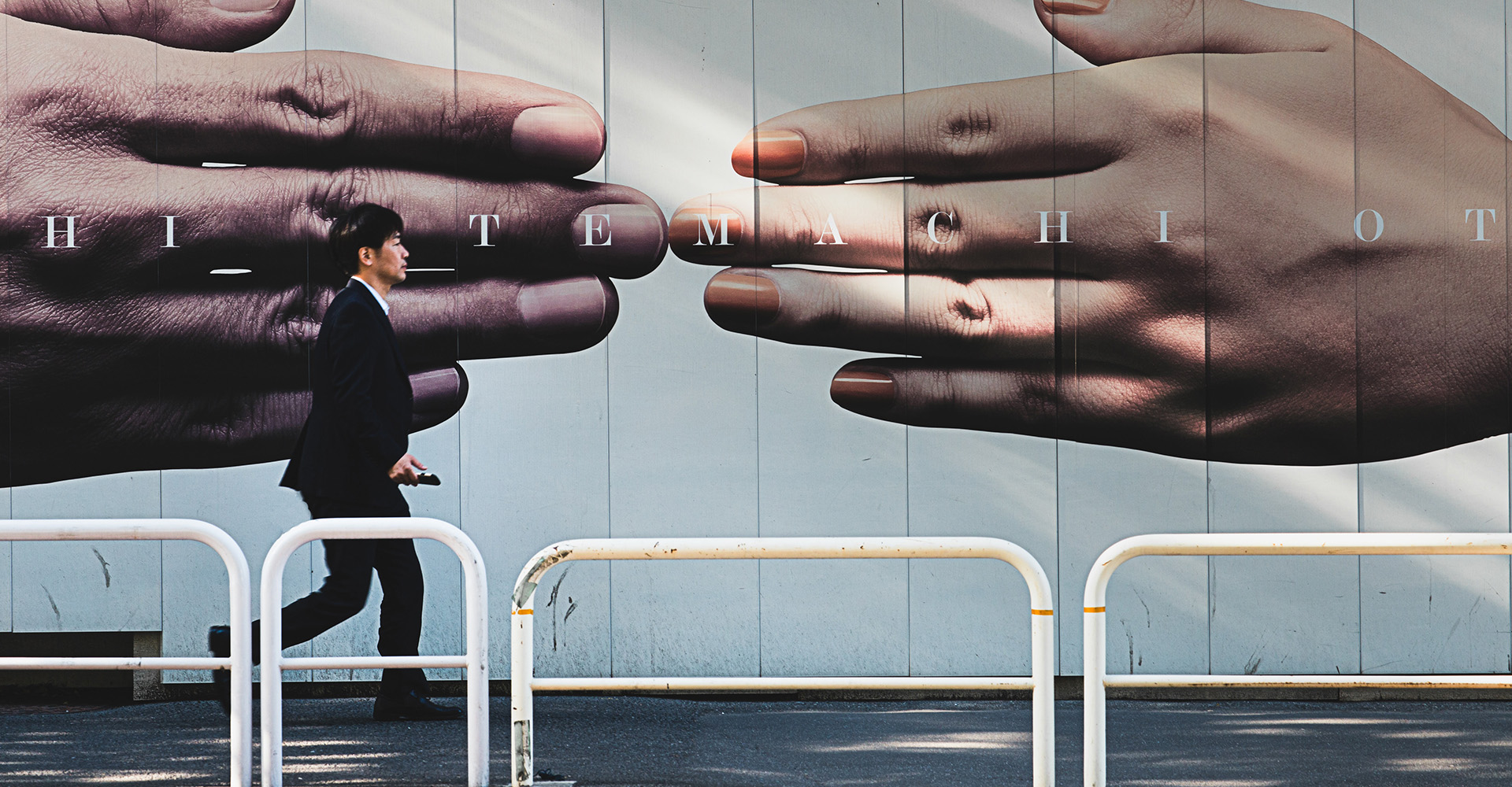 A person walking past a large format printed poster on a business wall