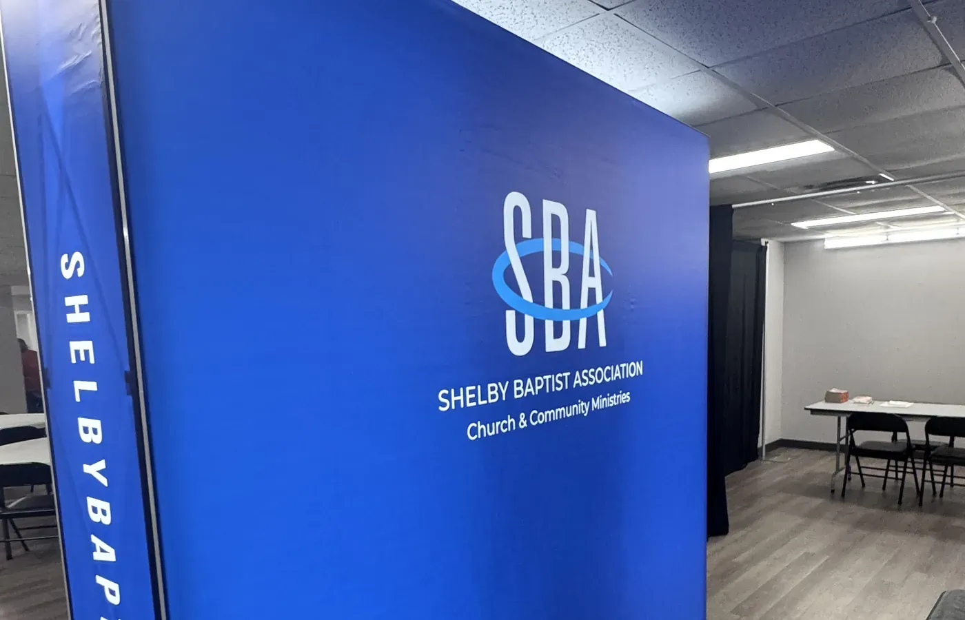 Blue backlit tension fabric display with Shelby Baptist Association logo and printed side panel