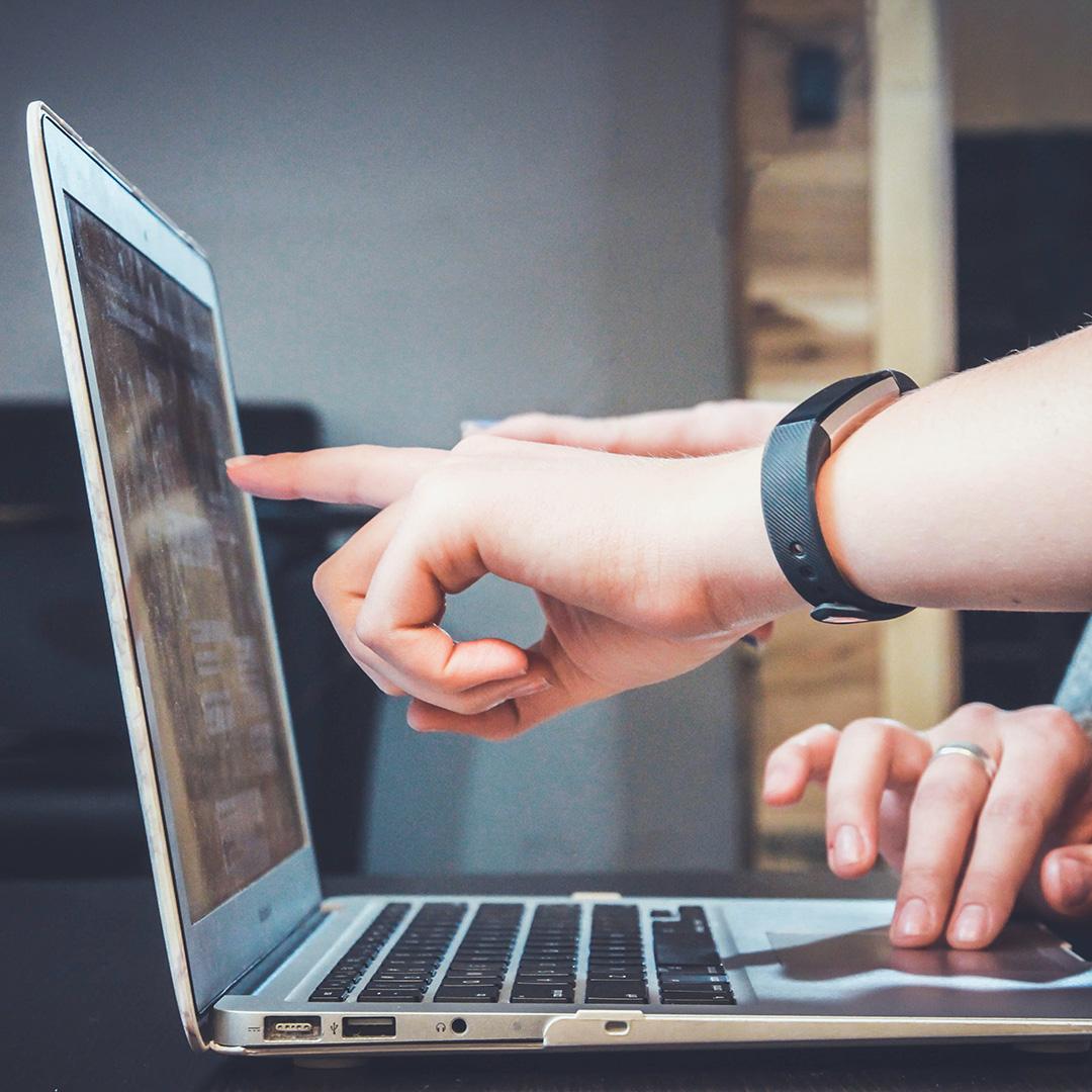 A person pointing at their computer screen