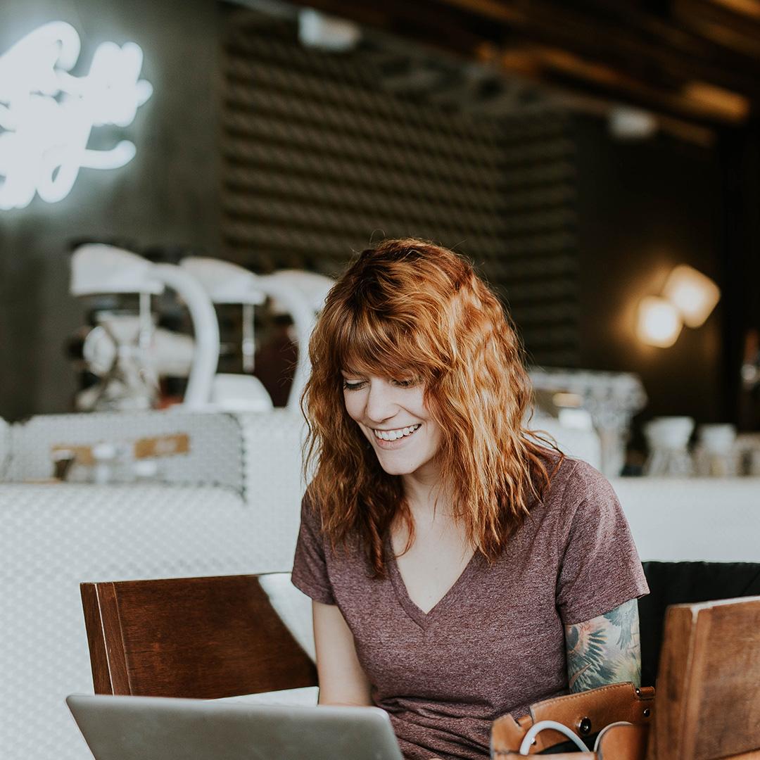 A happy cafe owner on her laptop at work