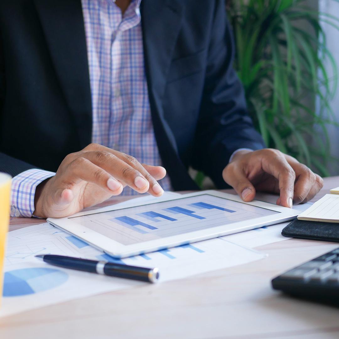 A businessman looking over financial paperwork and his tablet
