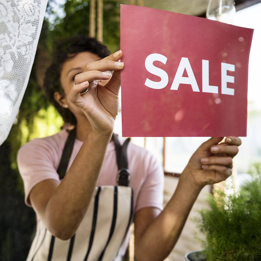 A woman hanging up a sale flyer