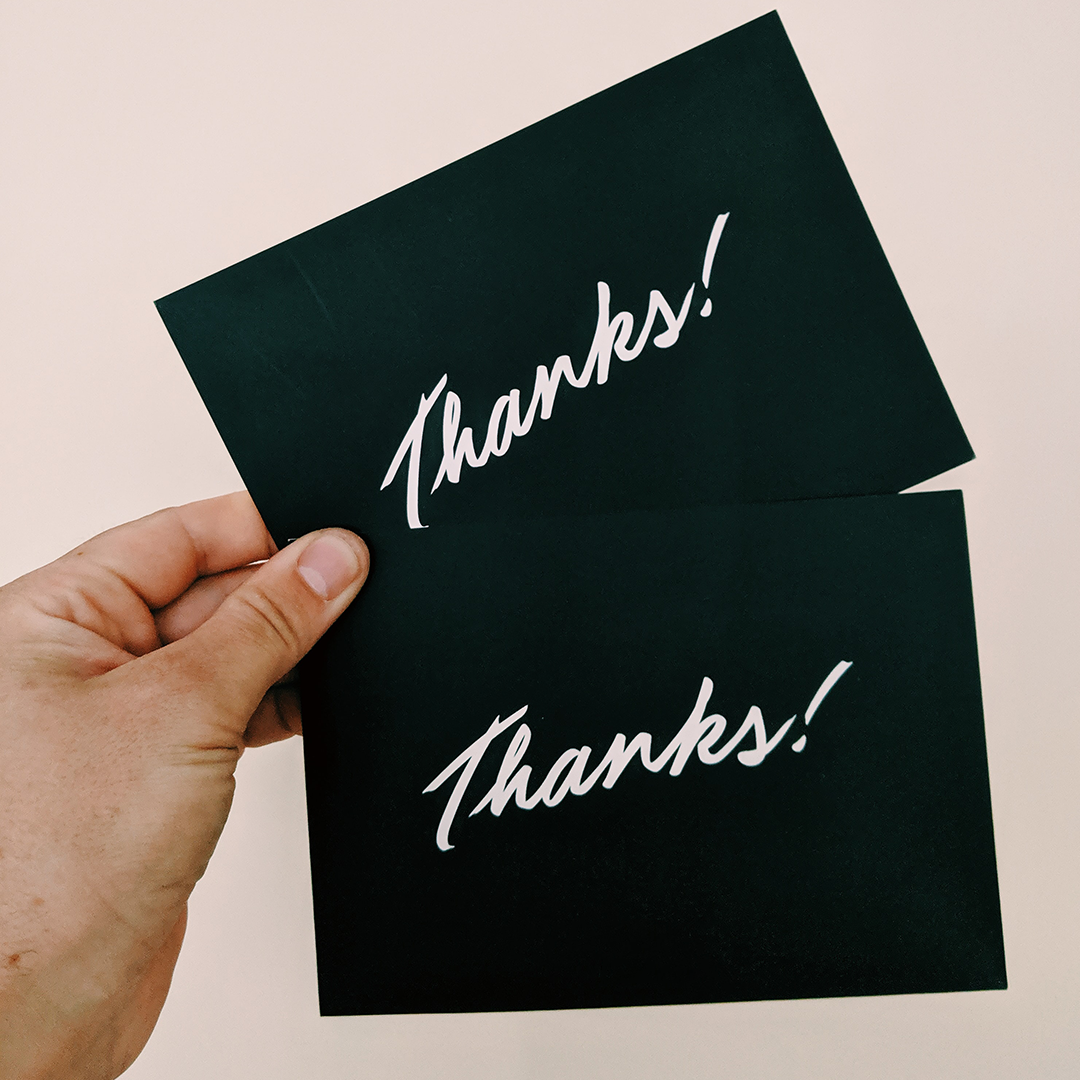 A hand holding two Thank You cards