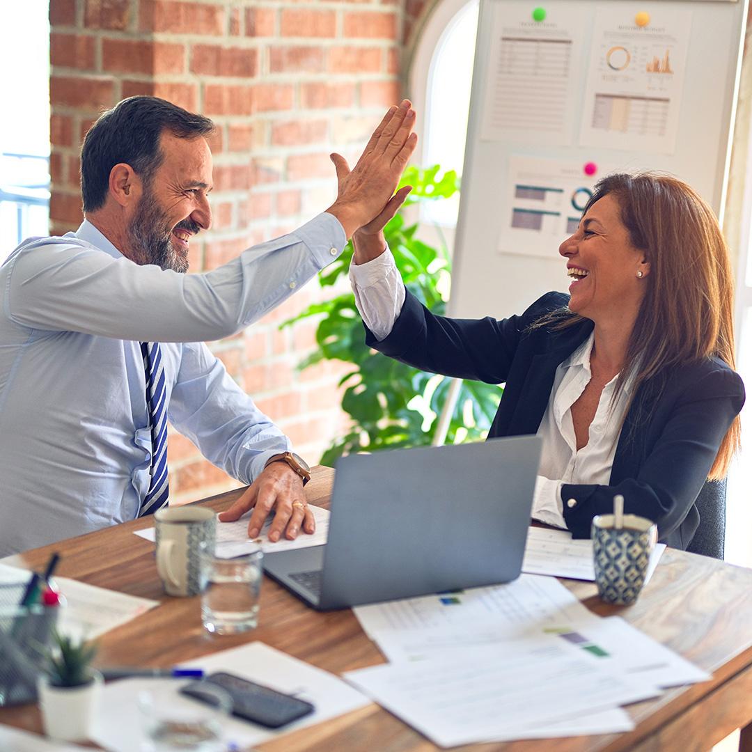 Two business colleagues high-fiving while in a meeting