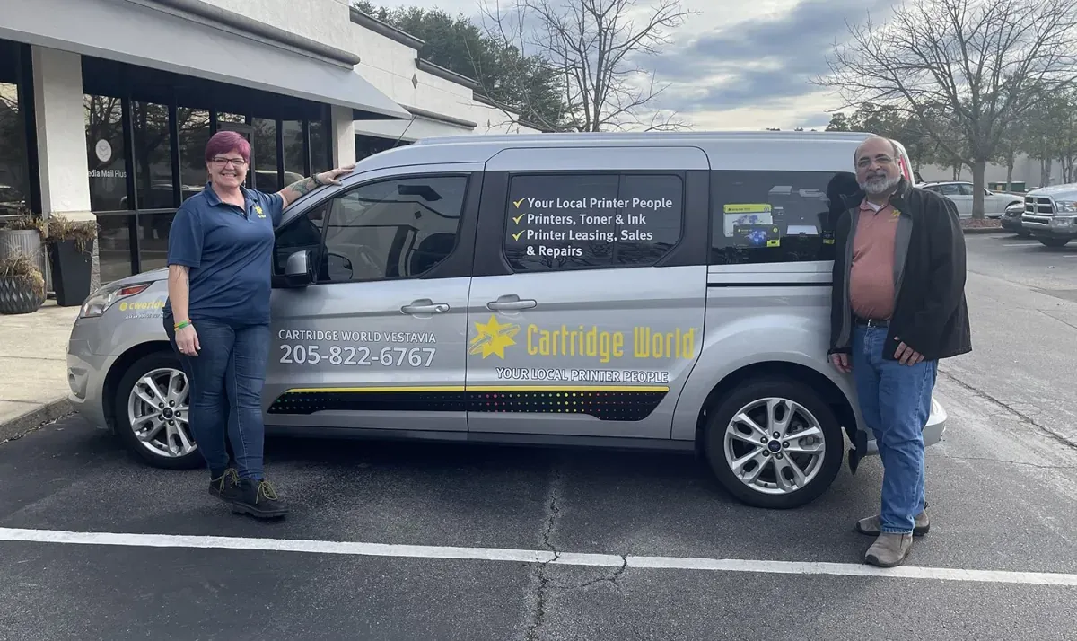 Cartridge World Vestavia van with custom lettering, shown with the business owners