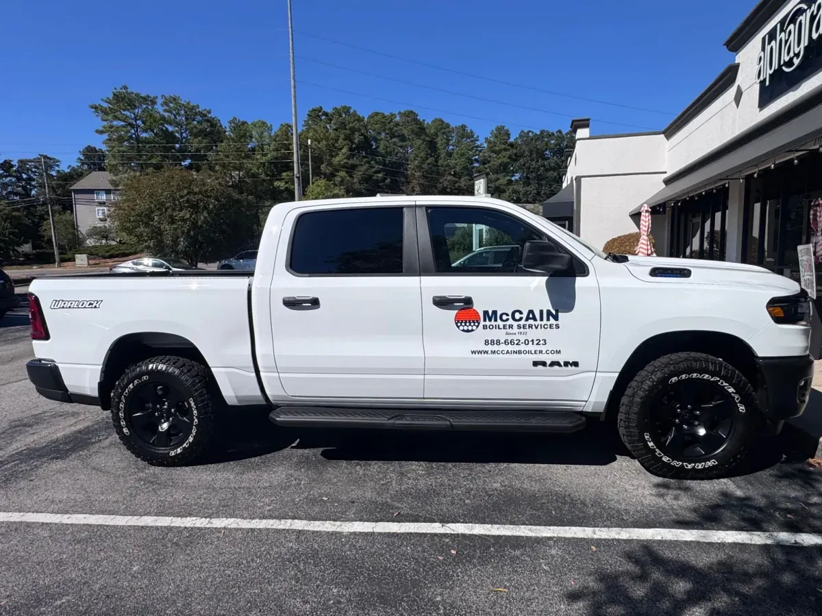 White Ram pickup with McCain Boiler Services door graphics, parked outside AlphaGraphics Hoover