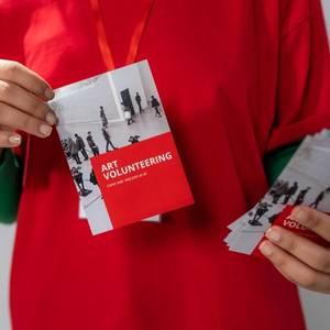 a person holding a red and white brochure