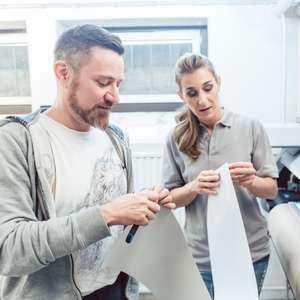 Two printing professionals working with materials for a large format print