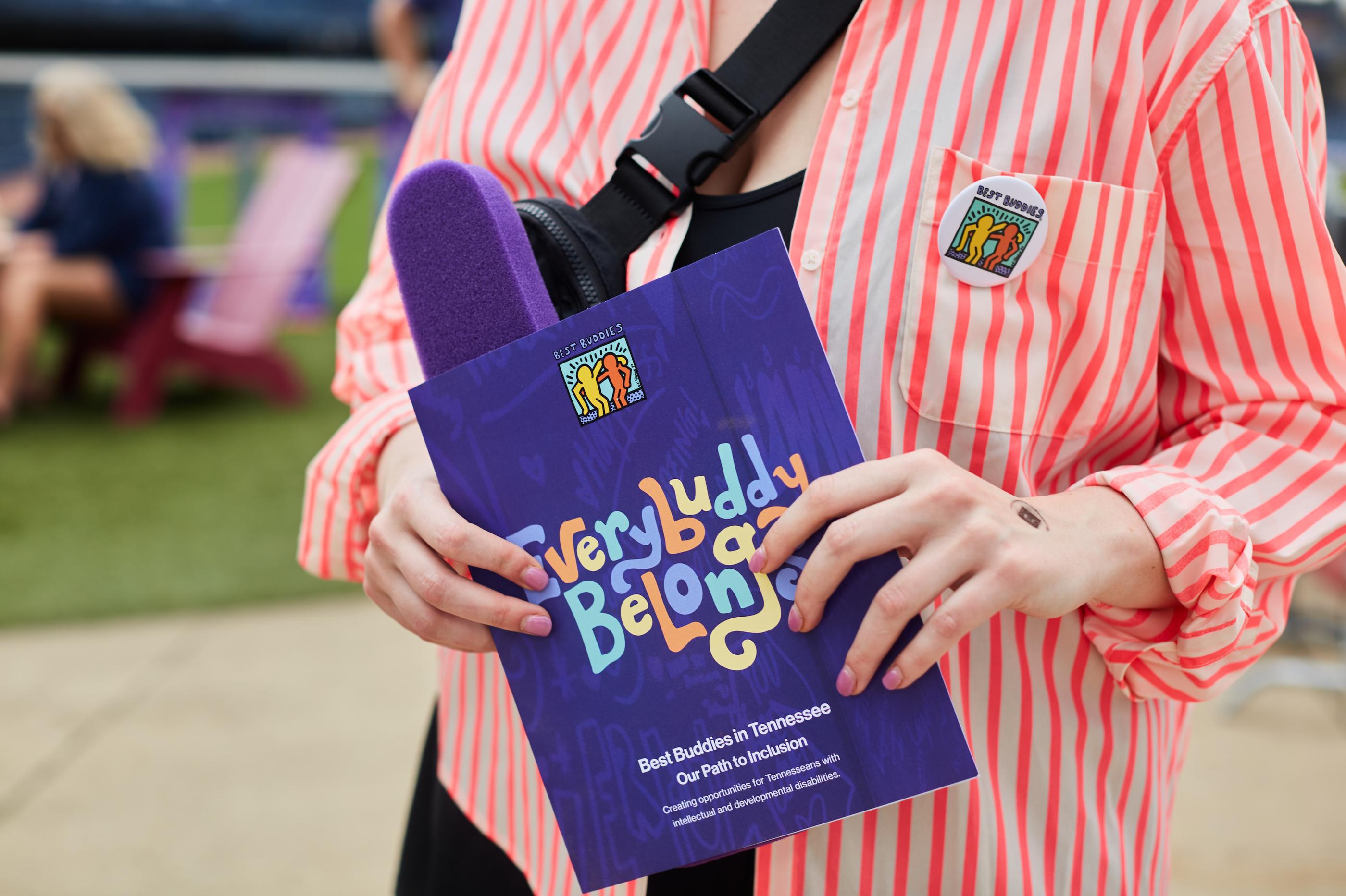 woman holding promotional content with 'Everybuddy Belongs' written on it
