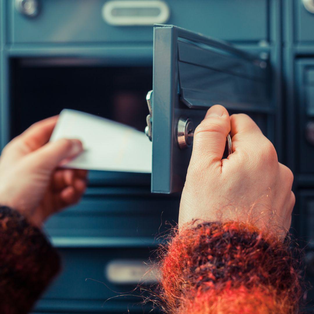Hands reaching into a mailbox and grabbing mail