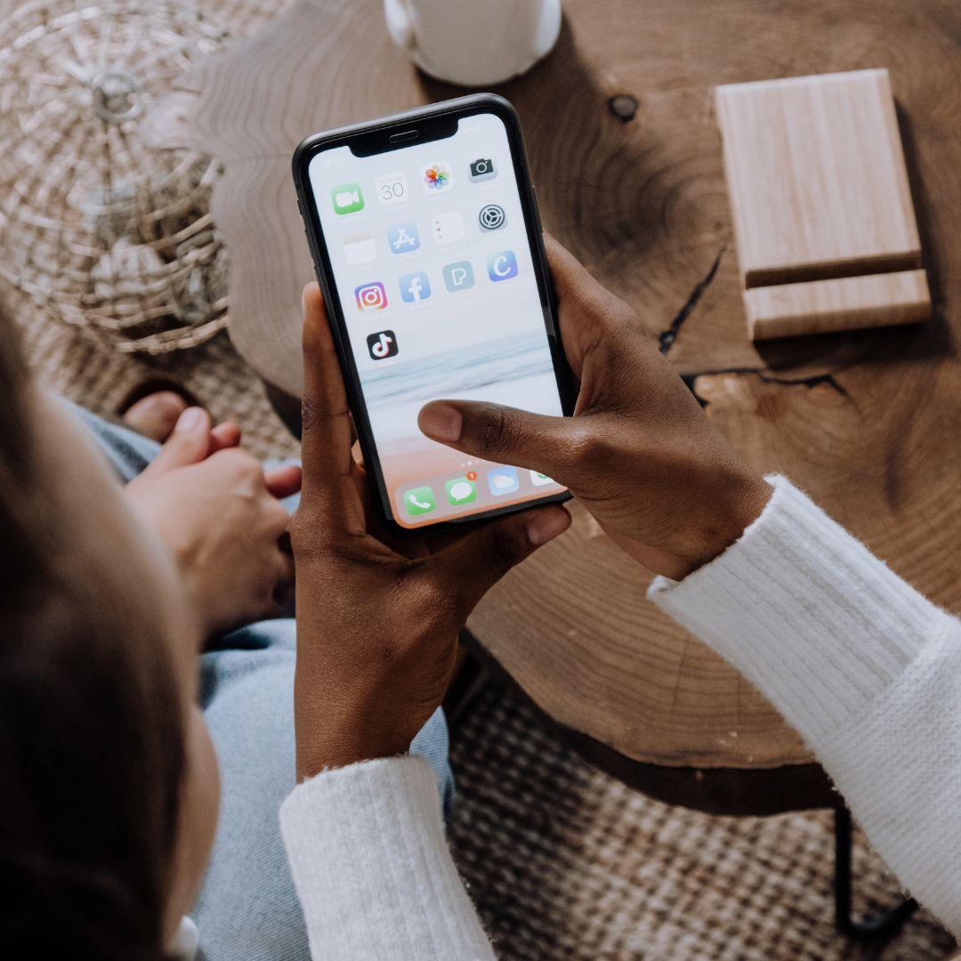 A woman holding her phone that is displaying her app icons