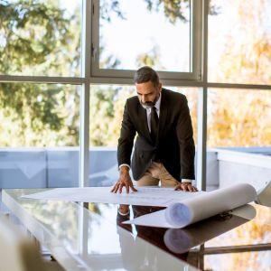 A businessman looking over a blueprint on a desk