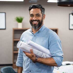 A happy businessman holding blueprints