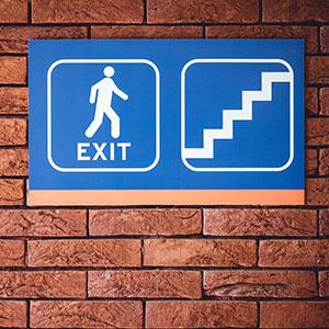 Exit signs on a brick wall inside a business