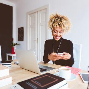 A woman looking at her phone while sitting in her kitchen