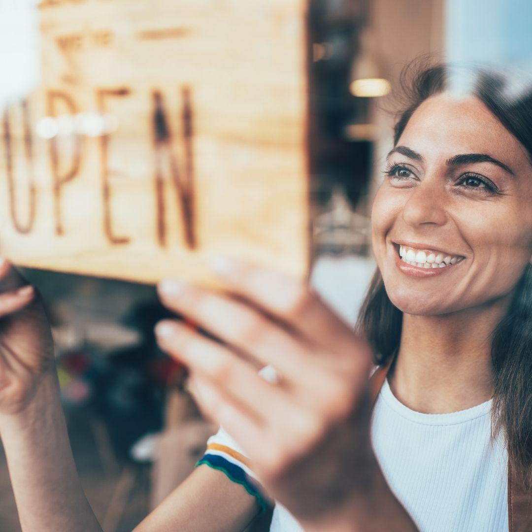 woman hanging up open sign
