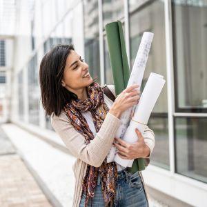 A young woman walking downtown with blueprints