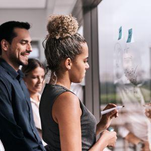 Business meeting with woman writing on window