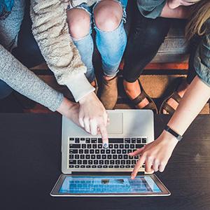 Three people pointing at computer screen