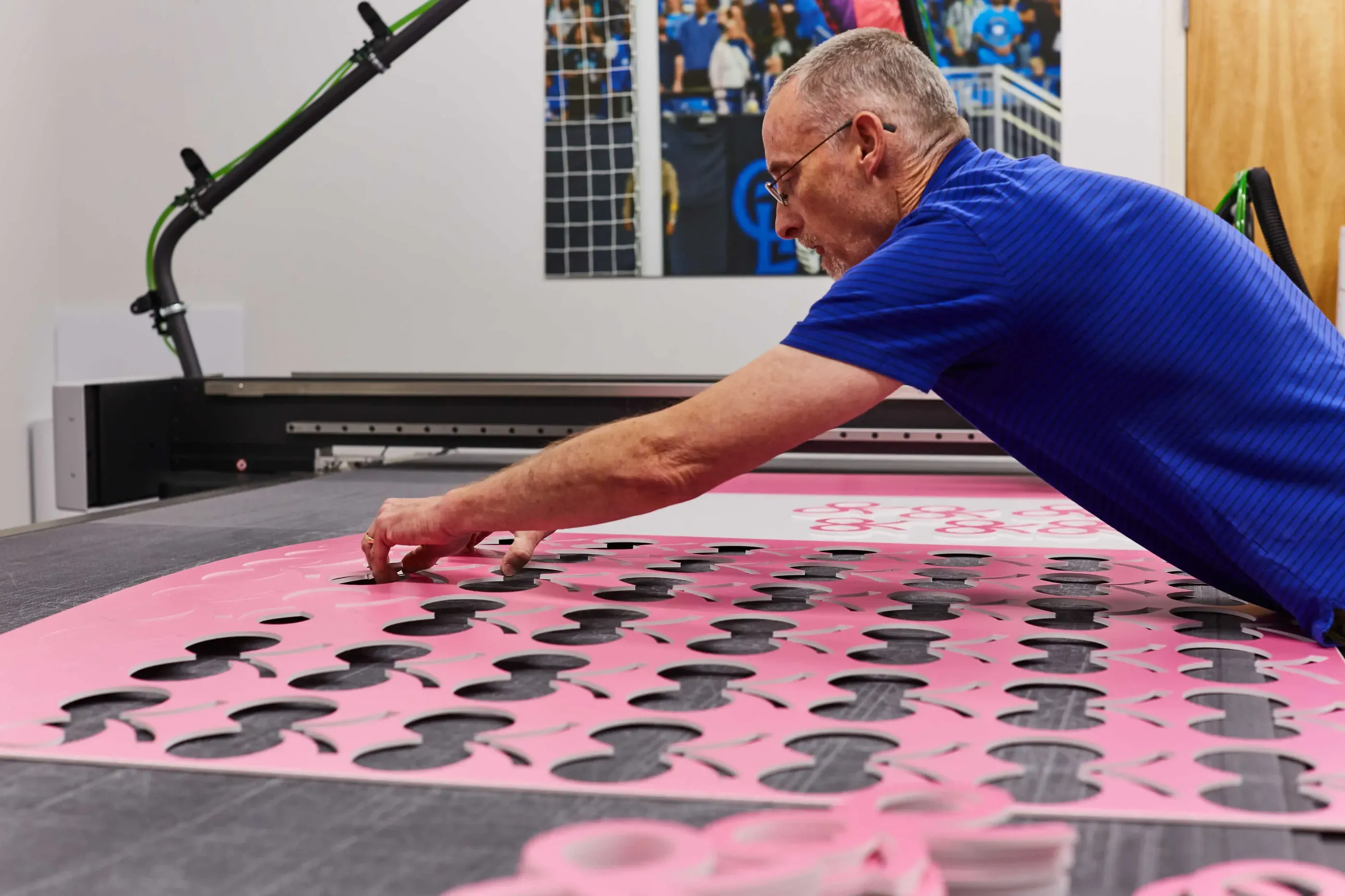 Man removing cut outs from large board on a table