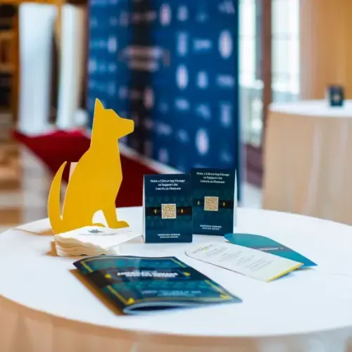 Cutout of a dog among napkins, brochures, and table tents on a table at a gala