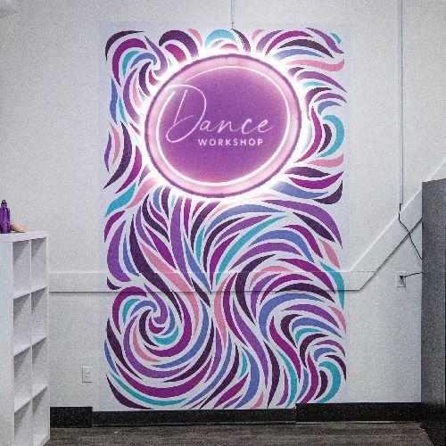 Neon sign for Dance Workshop above a mural