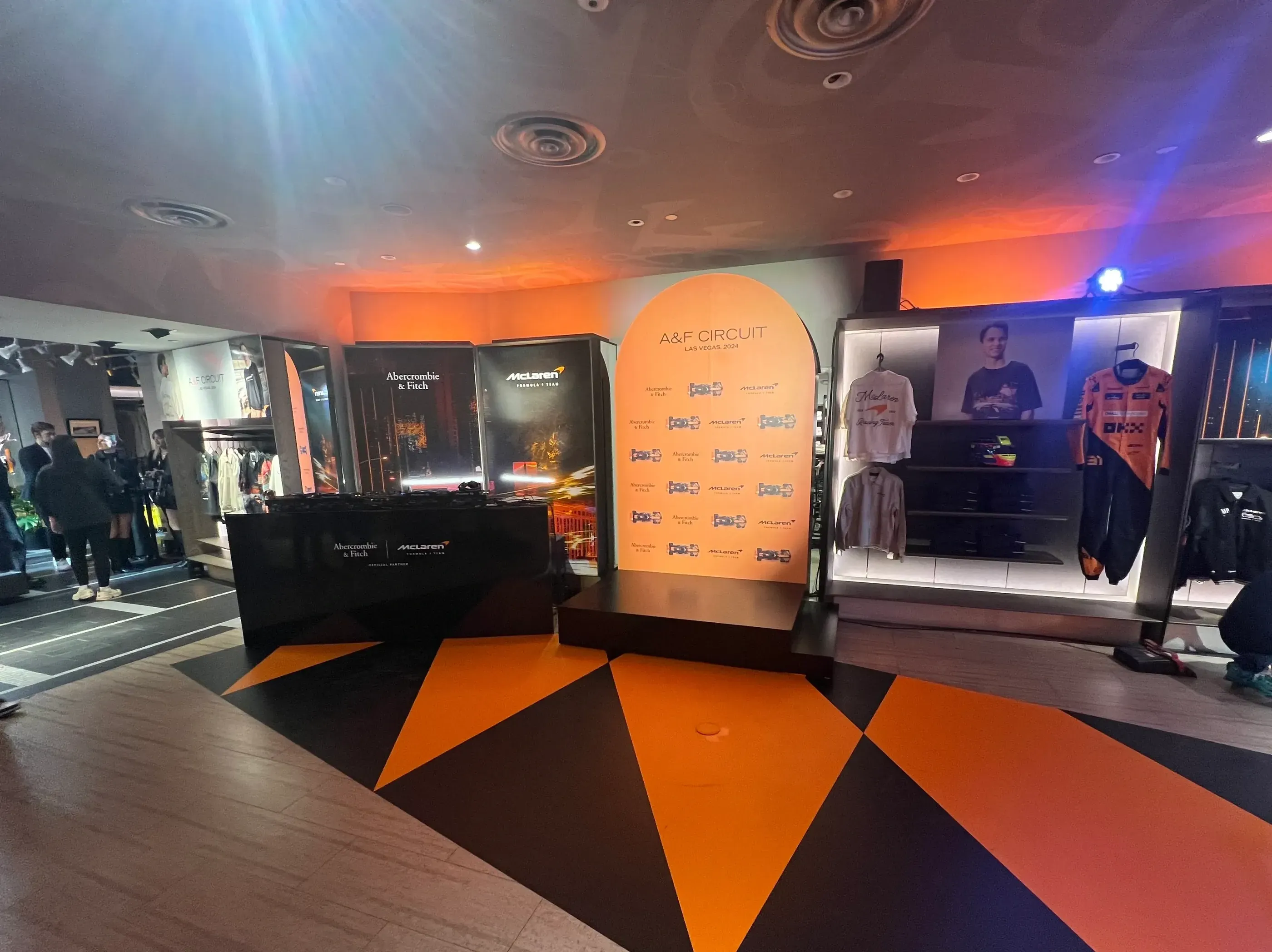 Branded wall signage inside a retail pop-up at the F1 Las Vegas Grand Prix, featuring logos for Abercrombie & Fitch and McLaren against a dramatic orange-lit backdrop.