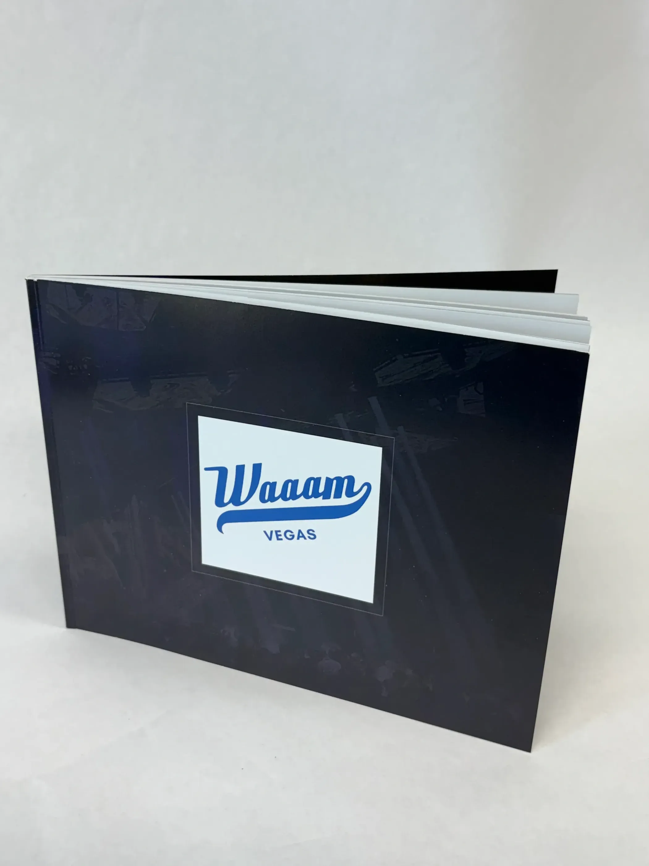 A landscape-oriented, perfect bound book with a glossy black cover and centered