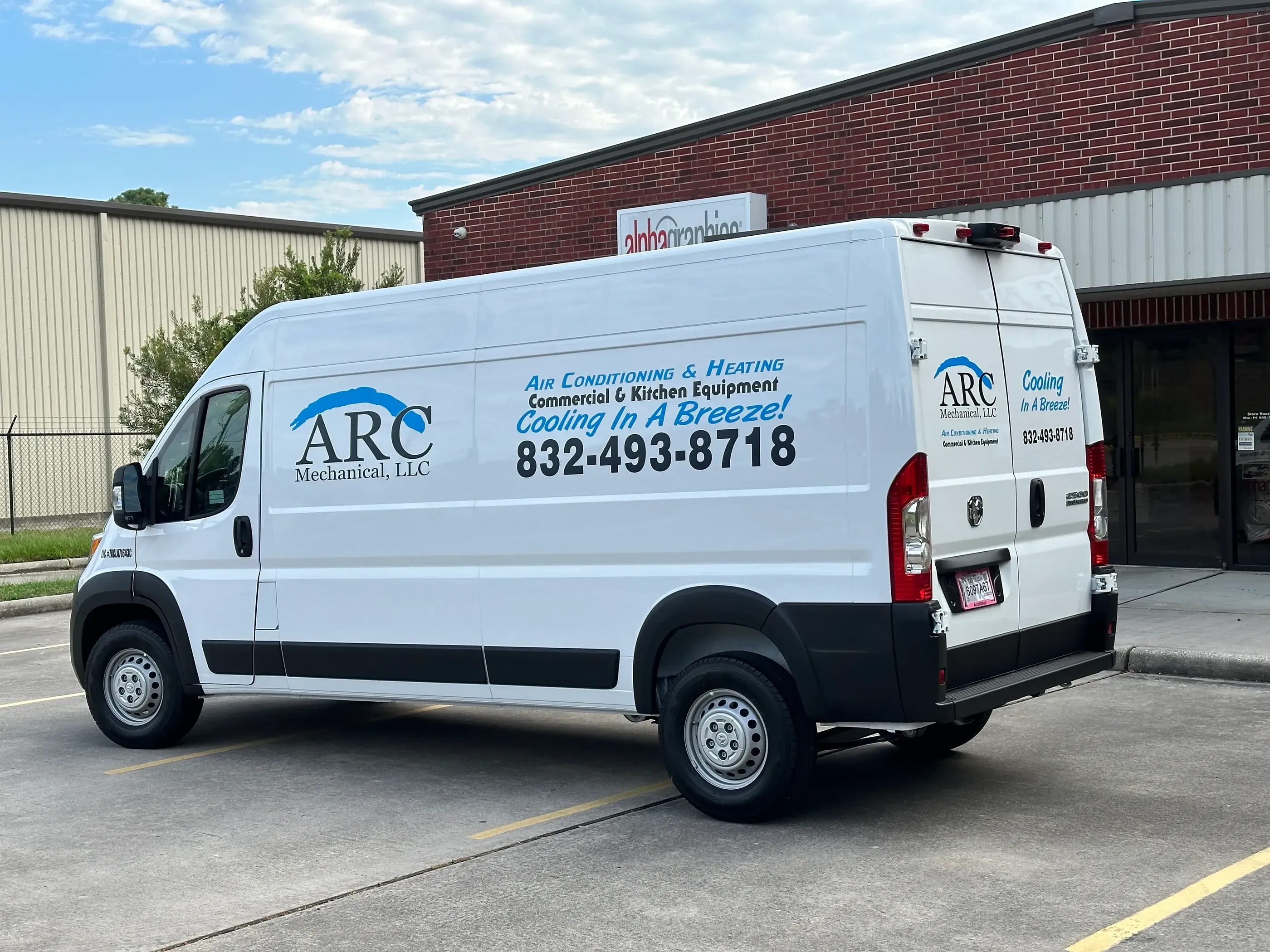 Side and rear view of a white van with ARC Mechanical, LLC branding. The side displays the company logo and contact details, while the back shows the slogan ‘Cooling In A Breeze!’ and phone number. The van is parked near an AlphaGraphics location.
