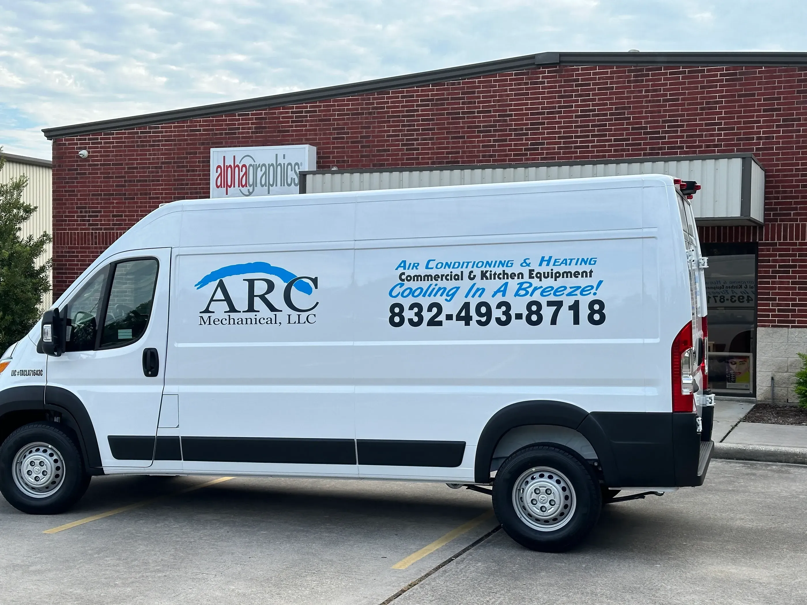 White van with ARC Mechanical, LLC branding on the driver’s side, including a blue wave logo and text reading ‘Air Conditioning & Heating, Commercial & Kitchen Equipment, Cooling In A Breeze! 832-493-8718,’ parked outside AlphaGraphics.