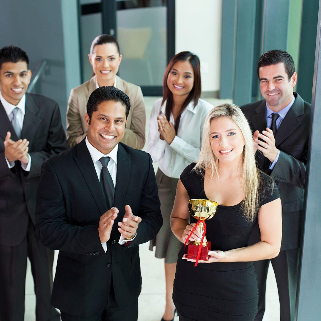 a group of employees celebrating a woman getting a business award