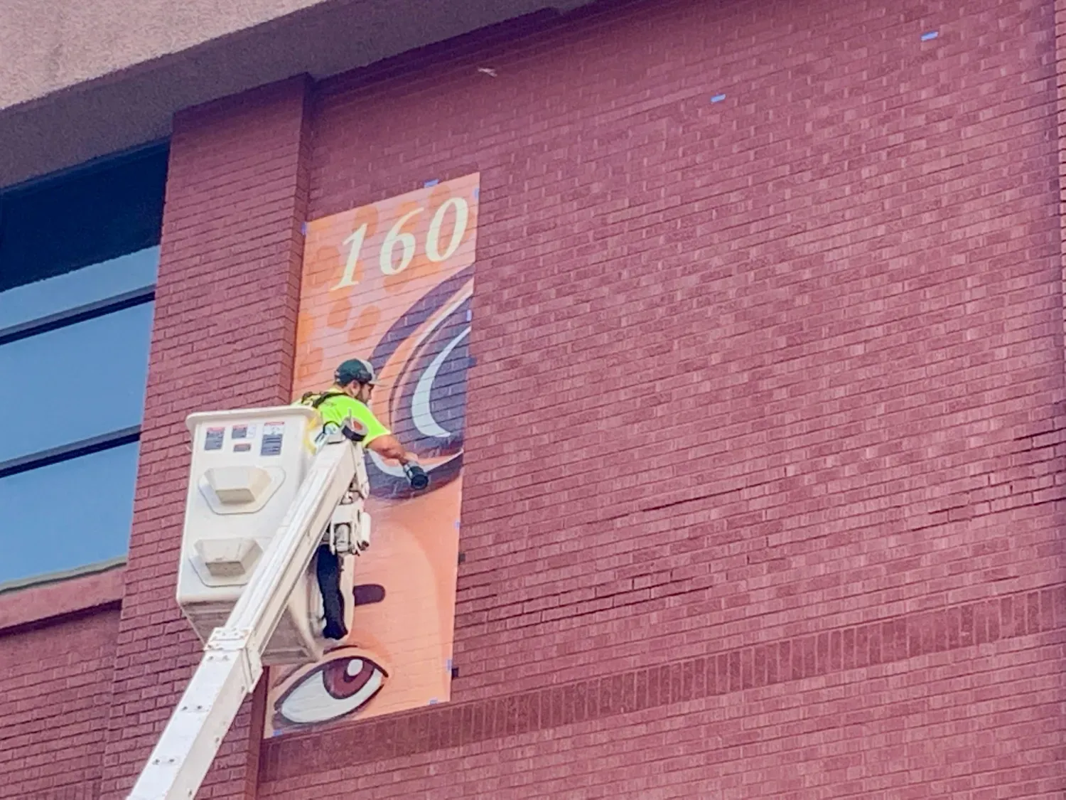 Construction workers installing a banner on a brick wall.