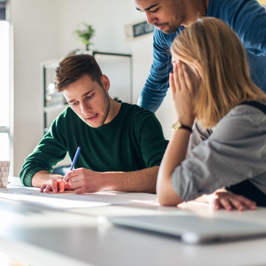 Three coworkers at a desk looking over a print project