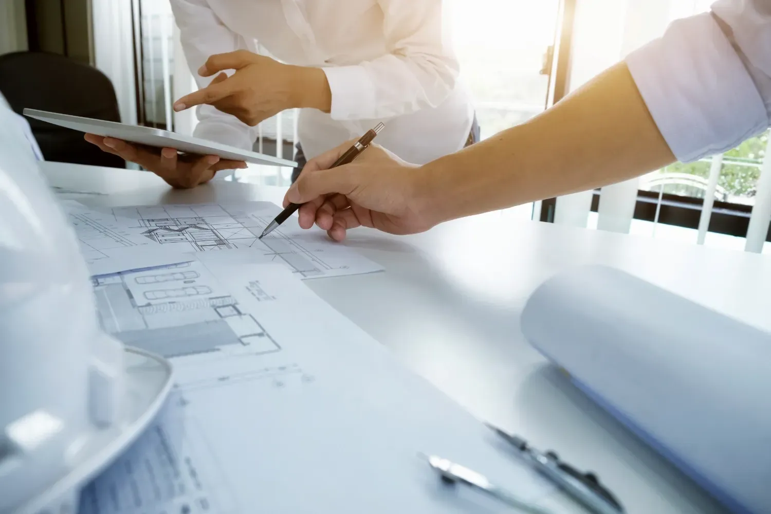 Two people reviewing a set of blueprints on the table.