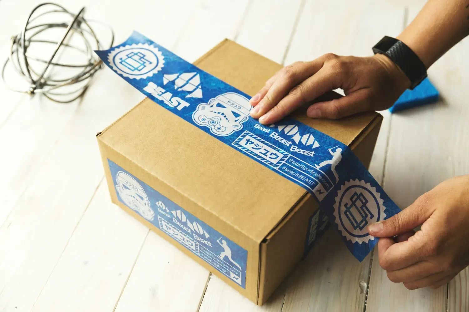 A person applying custom sticker tape to a shipping box.