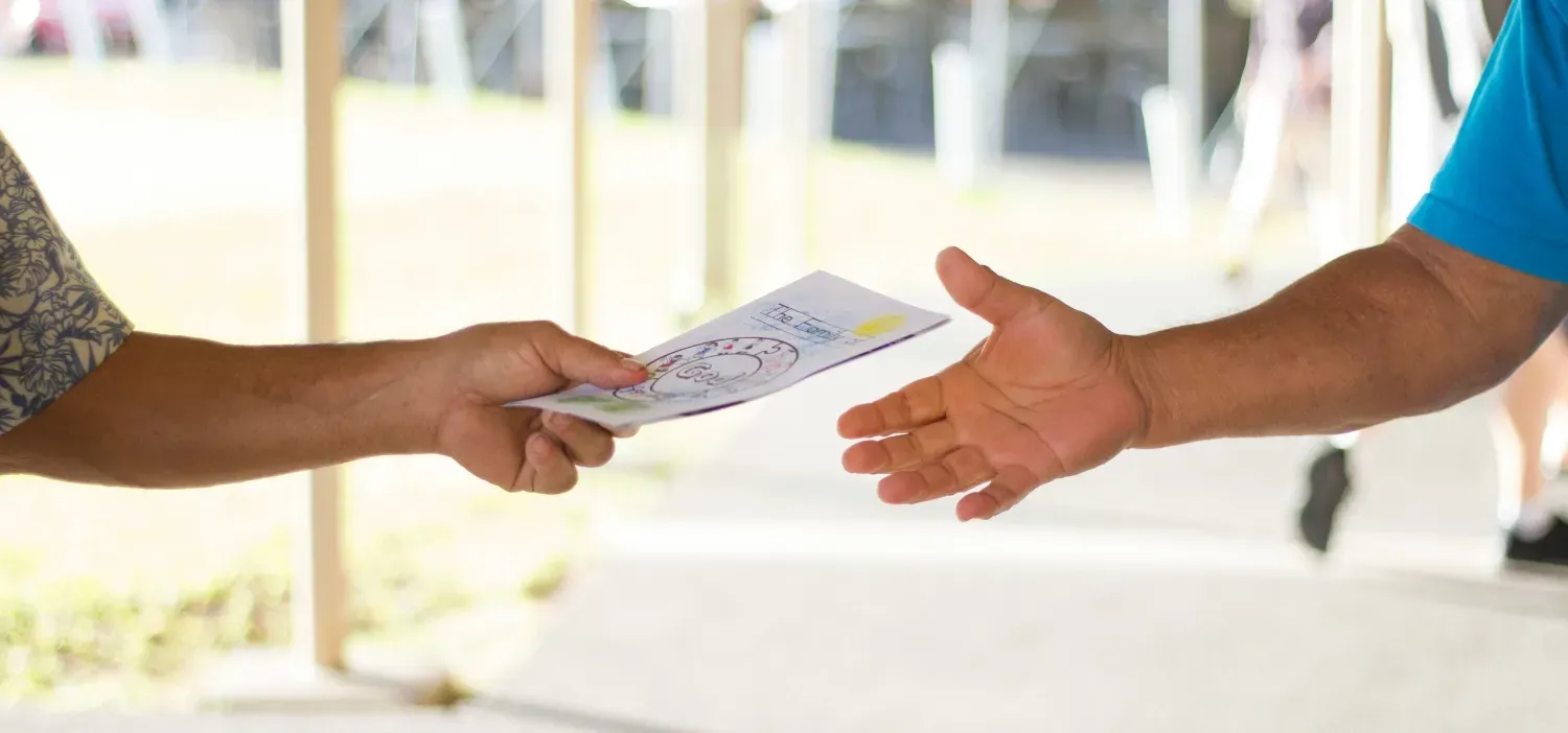 A person handing another person a printed flyer.