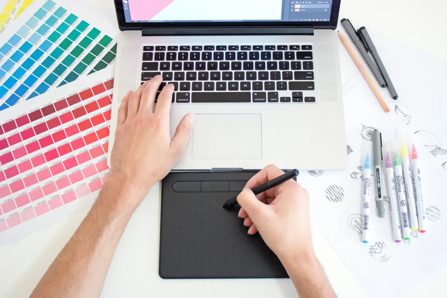Someone using a graphics tablet and laptop to make a design off-screen.