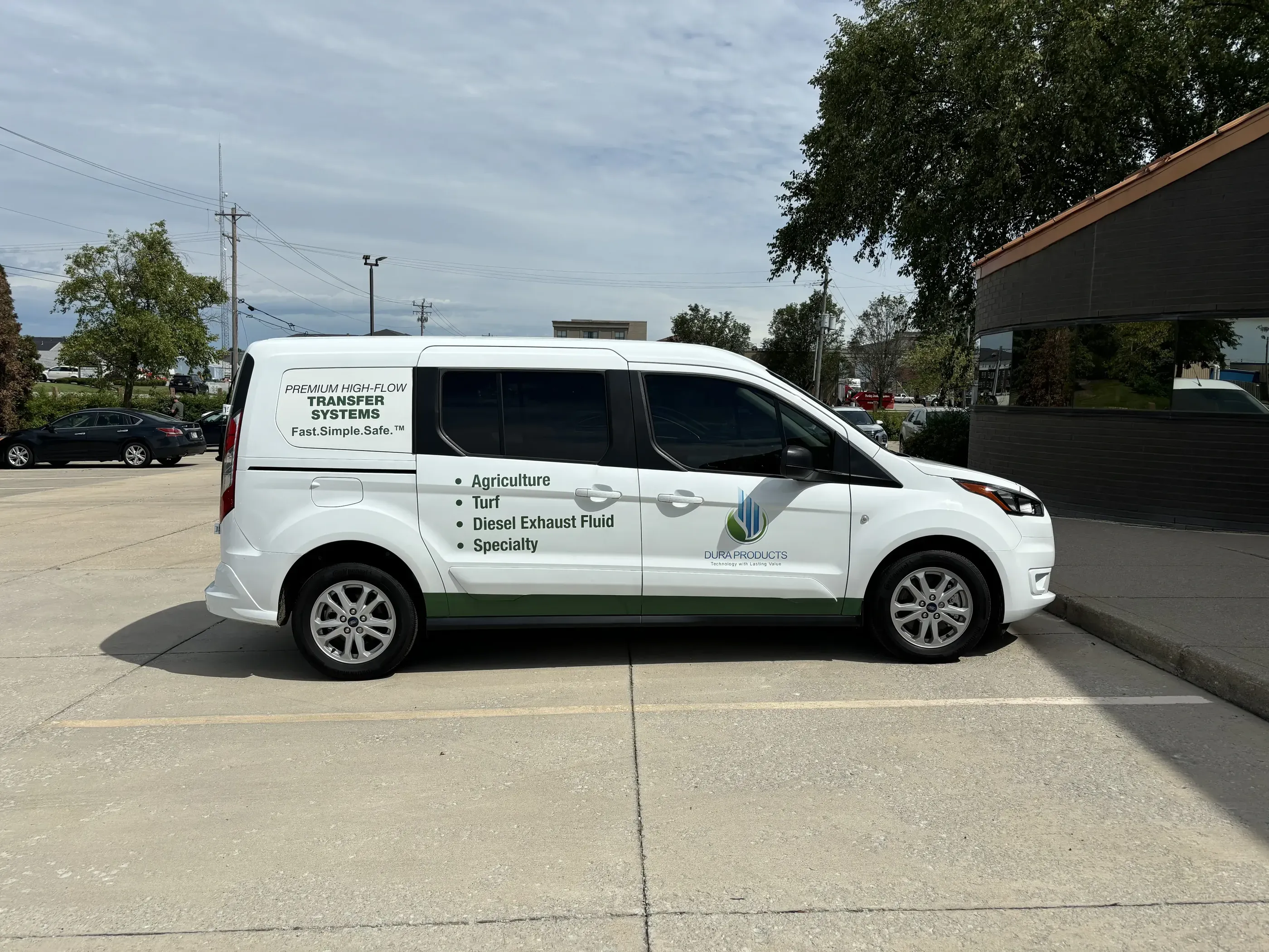 A white van with green accents branded for Dura Products. The vehicle features bold text highlighting services like agriculture, turf, diesel exhaust fluid, and specialty solutions, along with a clean logo and tagline.