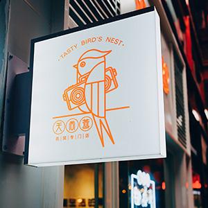 A white and orange business sign with a bird graphic