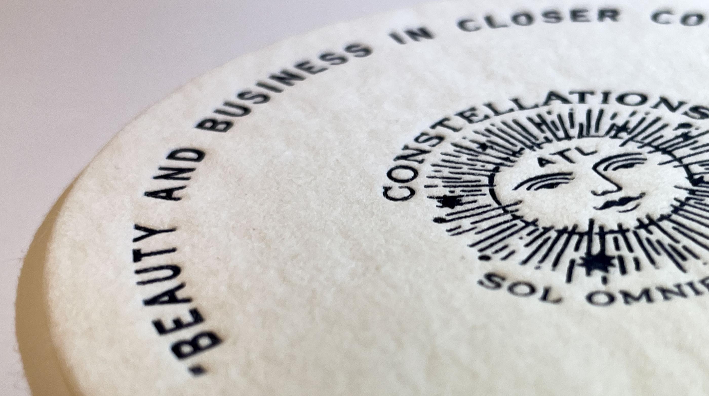 A close up of the texture a custom-printed coaster with black ink letterpress.